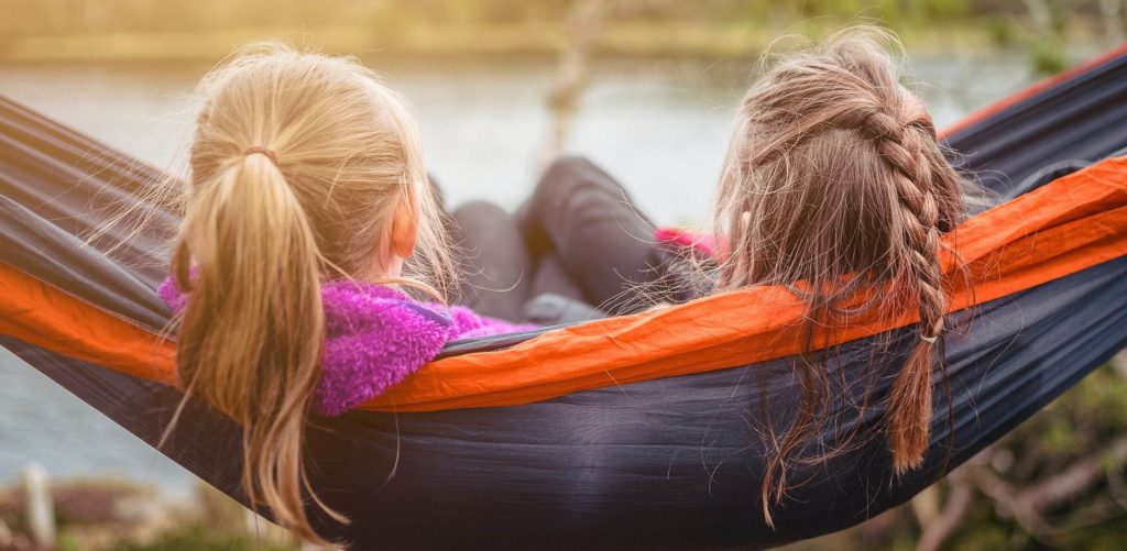 Zwei Kindera liegen in der Hängematte und unterhalten sich.